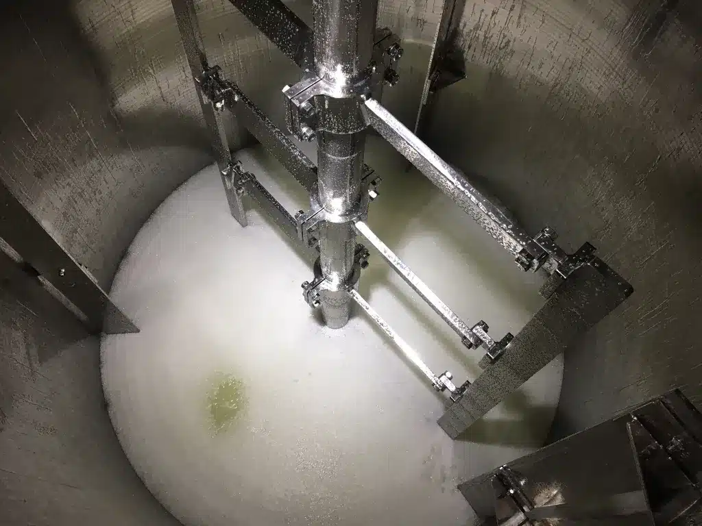 Vista interna de un depósito industrial con un agitador tipo áncora de AGITASER, fabricado en aleación resistente para procesos químicos corrosivos.